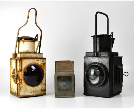 Three railway lamps, one painted cream with a red glass, height 51cm, one black with clear glass, height 48cm, and a small do