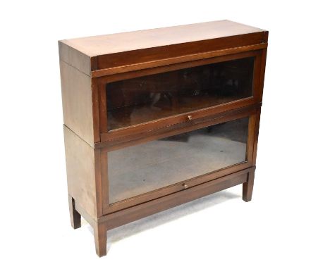 GLOBE-WERNICKE; a mahogany two-section stacking bookcase, each with up-and-over glazed doors, raised on tapering stile suppor