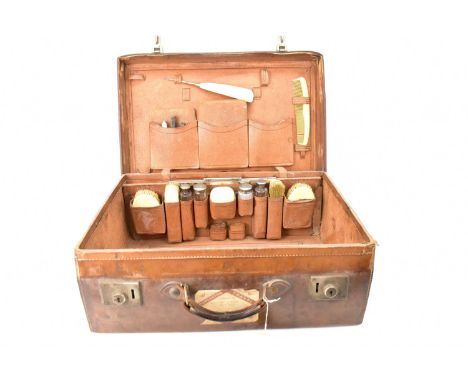 A large vintage brown leather travel case, with fitted interior and fitted pockets to the lid, containing various ivorine-han
