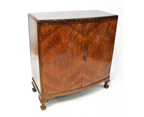 An early 20th century walnut bow-fronted two-door side cabinet, with quarter veneered panel doors, raised on squat cabriole l