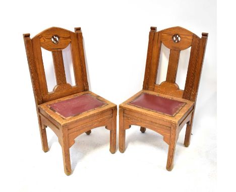 A substantial pair of pitch pine side chairs, with carved motif to the upper back panel and red leatherette seat pad, raised 