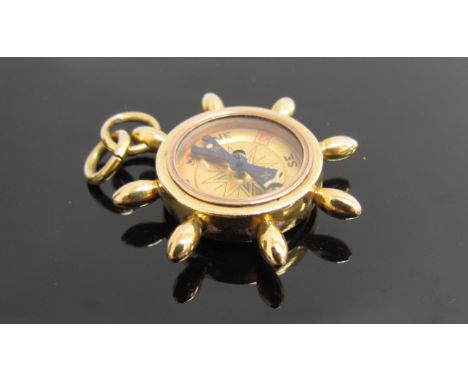 An 18ct gold charm compass in the form of a ships wheel, 12.6g