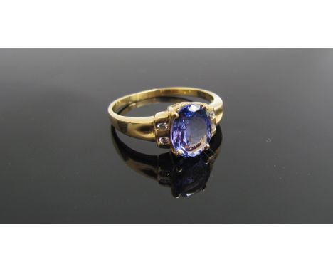 An 18ct gold tanzanite ring, the oval stone flanked by diamonds. Size R, 3.8g 