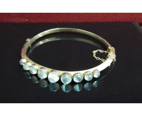 A 9ct gold stiff hinge bangle with graduated cabochon moonstones, stamped 9c, 8.5g 