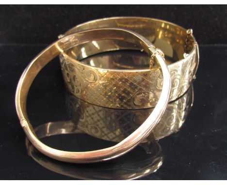 A 9ct gold bangle, dented, 8.5g and a 9ct gold plated engraved stiff hinge bangle