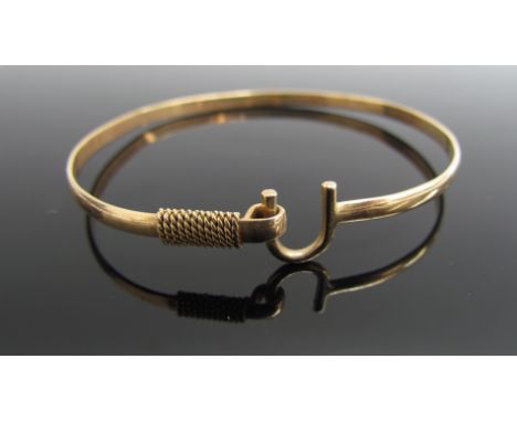 A gold bangle with horseshoe shaped fastening, stamped 14k, 6.5g