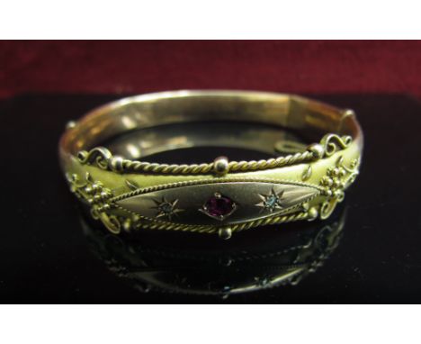 A Victorian 9ct gold bangle with scroll detail set with small old cut diamonds and ruby (dented), 10.4g