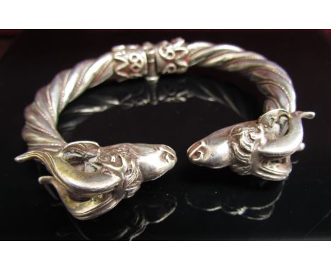 A heavy twisted white metal bangle with rams head terminals and locking hinge, stamped 900. 85.4g