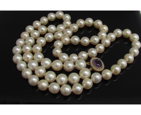 A cultured pearl necklace with gold clasp set with amethyst cabochon, 64cm long