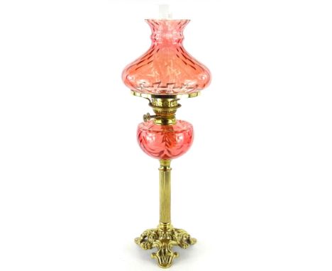 A Victorian style brass oil lamp, with cranberry tinted shade and reservoir, on column base, 65cm H.