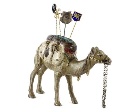 A cold painted model of a pin cushion, modelled in the form of a camel, stamped to the underside Geschutz and four stick pins