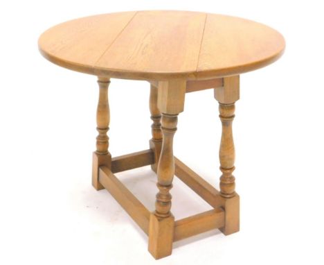 A small light oak oval drop leaf table, on turned legs, 59cm W.