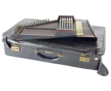 A German auto harp, with stained and ebonised wood, ivorine keys, etc., and a suitcase.