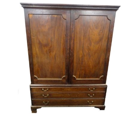 A George III mahogany clothes press, the top with a blind fret cornice above two panelled doors enclosing a partly fitted int