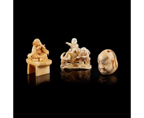 Y GROUP OF THREE IVORY NETSUKE MEIJI PERIOD comprising: one carved with two faces against each other, one younger and one bea