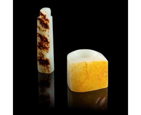 GROUP OF TWO JADE PIECES comprising: a pale celadon-coloured thumb ring cleverly features the brownish orange skin to one sid