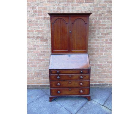 A GEORGIAN OAK BUREAU with fall front above four long graduated drawers with turned handles and raised on bracket feet, and w
