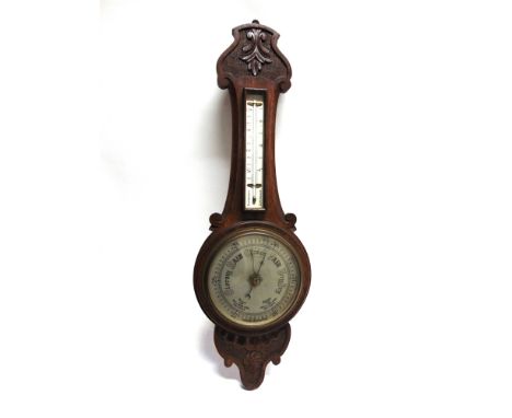 AN EDWARDIAN CARVED OAK BAROMETER/THERMOMETER with 8" silvered dial, 83cm high