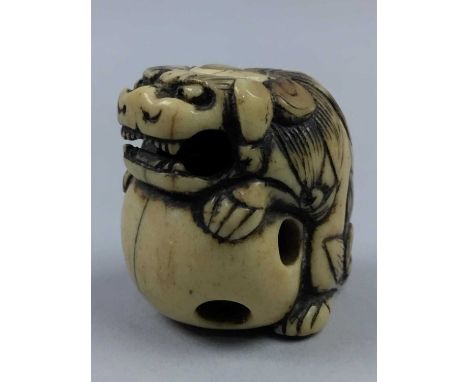 JAPANESE IVORY NETSUKE,Meiji period, depicting a lion dog, the base inset with a mother of pearl flowerhead, 2.5cm high