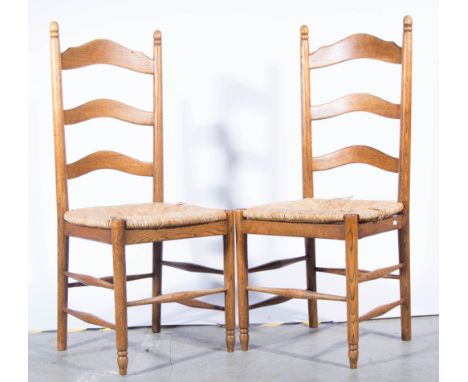 Set of four oak ladder-back chairs, rush seats, the legs joined by turned rails, width 46cm.