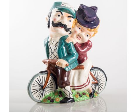 Shorter pottery lamp base, designed with a lady and gentleman riding a tandem, painted in colours, height 27cm.