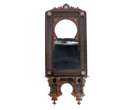 A large Anglo-Moorish wall mirror probably retailed by Liberty & Co, in two sections, the lower section with shelf, set with 