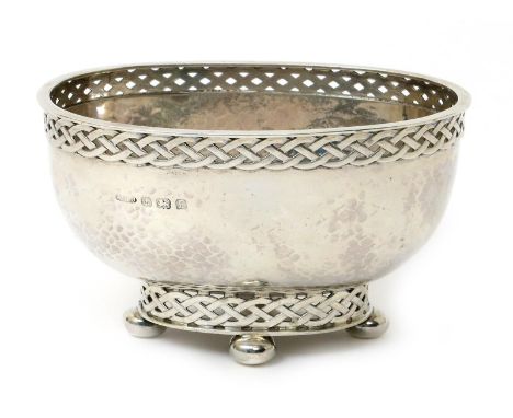 An A.E. Jones silver Celtic basin, raised on four bun feet the pierced Celtic border foot supporting flaring hammered bowl wi