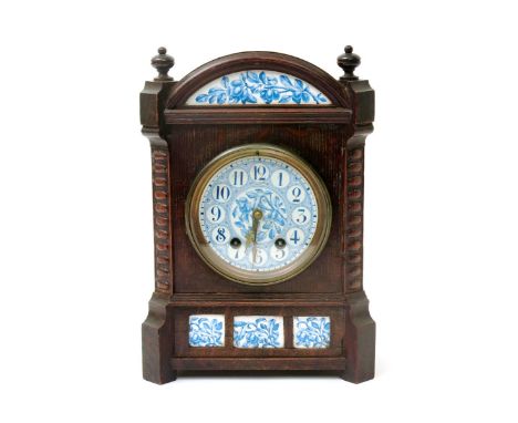 An Aesthetic Movement oak mantel clock in the style of Lewis F Day, rectangular  form with domed mantel, set with enamelled p