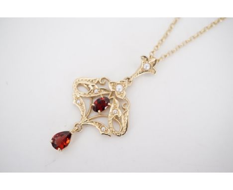 A 9ct gold, garnet and seed pearl pendant necklace of Art Nouveau style, in an openwork arrangement, on a 9ct gold belcher-li