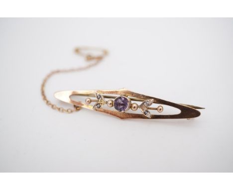 A Belle Epoque yellow metal openwork bar brooch, set with a central amethyst coloured glass stone, flanked by split-seed pear