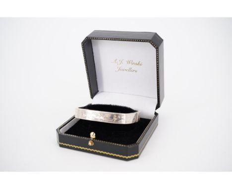 A white metal bangle, of rounded square section, bright-cut engraved to the circumference, 6 cm internal diameter, 20.6g