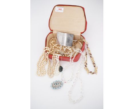 A vintage red travel jewellery case containing costume necklaces, including faux pearls and paste, and a Scottish kilt / plai