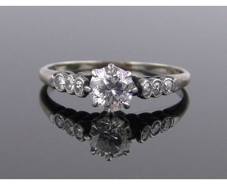 An 18ct gold and platinum 0.5ct solitaire diamond ring, small diamond set shoulders, size K.