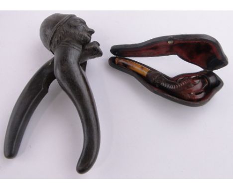 A Black Forest carved wood nutcracker in the form of a man's head, length 17cm and a Victorian carved amber eagle's claw pipe