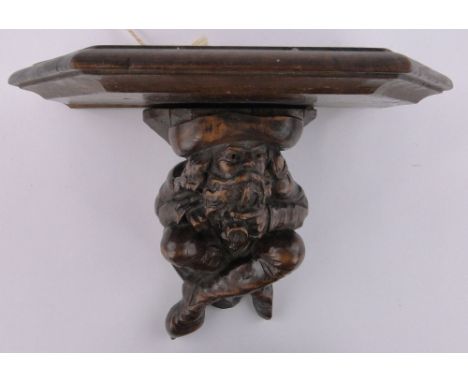 A 19th century German carved stained wood wall bracket, supported by a figure of a man smoking a pipe, shelf width 32cm, over
