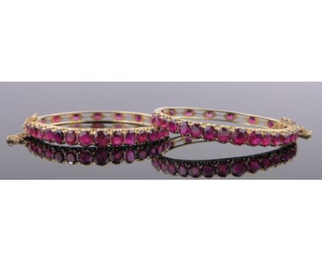 A pair of high carat gold ruby set hinged bangles, total ruby content approx. 23cts with certificate stating natural Burmese 
