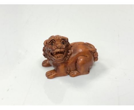 A carved Chinese hardwood netsuke - Lion seated