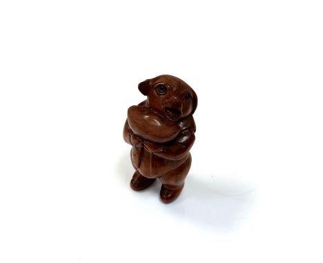 A carved Chinese hardwood netsuke - Pig holding a bowl