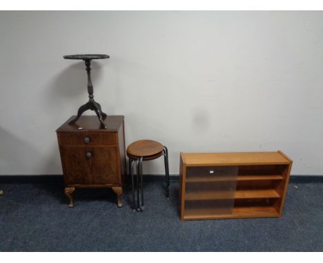 A small teak sliding glass door bookshelf together with a set of three wood and metal stools, a leather inset tripod occasion