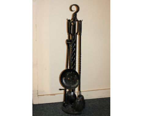 A free standing set of five fire tools, black painted cast iron, on horse shoe shaped base, 90cm high