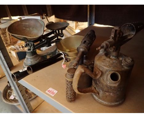 Two brass blowlamps with two brass metal handled sauce pans and a set of balance scales