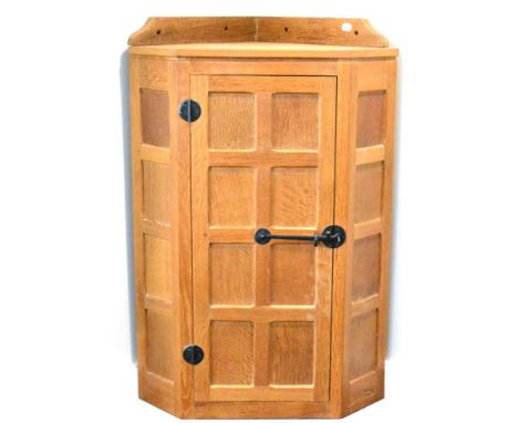 A Robert ''Mouseman'' Thompson Panelled Oak Hanging Corner Cupboard, the single door opening to reveal two fixed shelves, wro