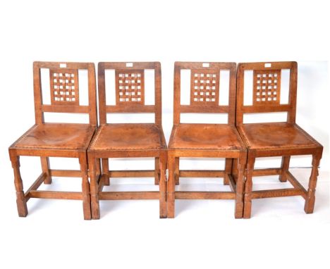 A Set of Four Robert ''Mouseman'' Thompson Oak Lattice Back Dining Chairs, with cow hide upholstered seats, on two octagonal 