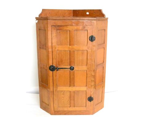 A Robert ''Mouseman'' Thompson Panelled Oak Hanging Corner Cupboard, the single door opening to reveal three shelves, wrought