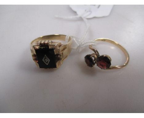 A cross over style ring set with two garnets, stamped '9ct' and an onyx set signet ring stamped '10K' 6.7g gross (2)  
