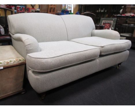 A modern upholstered two seater sofa, on turned front legs and brass casters  