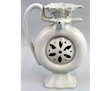 A white glazed puzzle jug, the pierced rim with three nozzles and scrolling handle, over a ring shaped body pierced to the ce