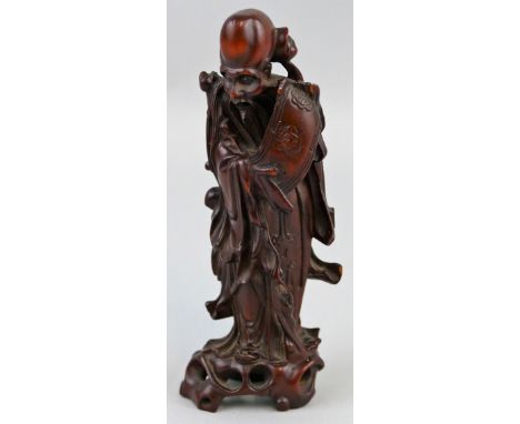 A Chinese hardwood figure of Shou Lao, well carved from the solid standing unrolling a scroll, 15 cm high.