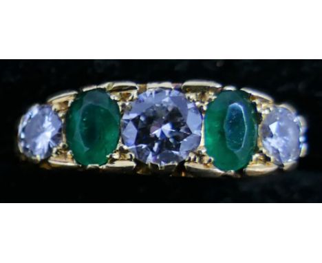 An 18ct gold five stone emerald and diamond ring, carved claw set with oval mixed cut and brilliant cut stones, diamond weigh