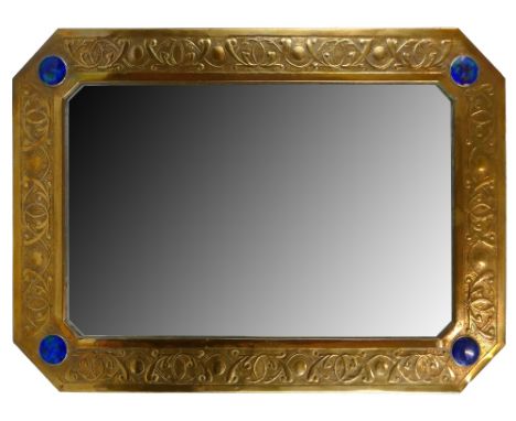 An Arts and Crafts style brass framed wall mirror, in the manner of Liberty and Co., of octagonal form embossed with scrollin